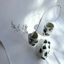 Load image into Gallery viewer, Three ceramic vases, each appearing to be slightly squished, sit on a piece of white paper. One is toppled over and one has dried flowers in it. Each one is white with navy splotches.
